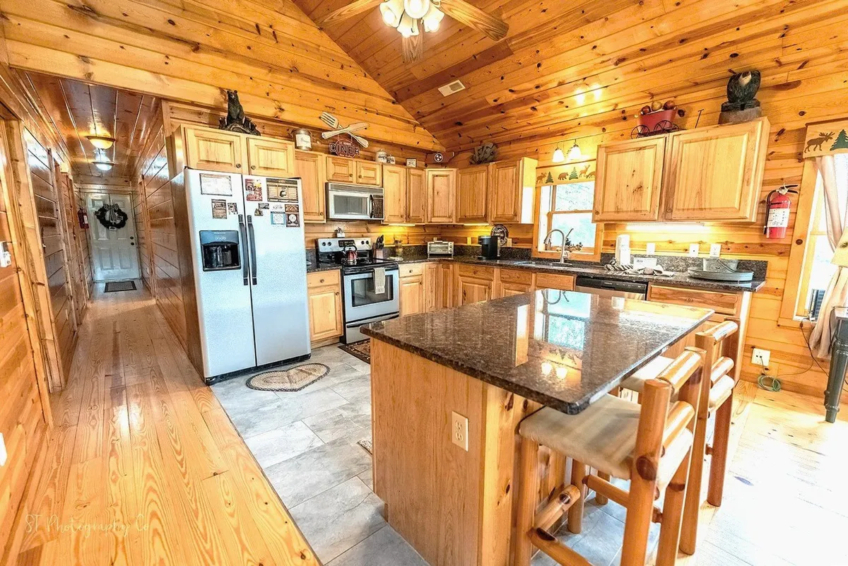 This image showcases the kitchen area with a prominent central island, stainless steel appliances, and warm wooden cabinetry. The space is bright, inviting, and ready for culinary adventures, perfectly reflecting the open kitchen described in the section.