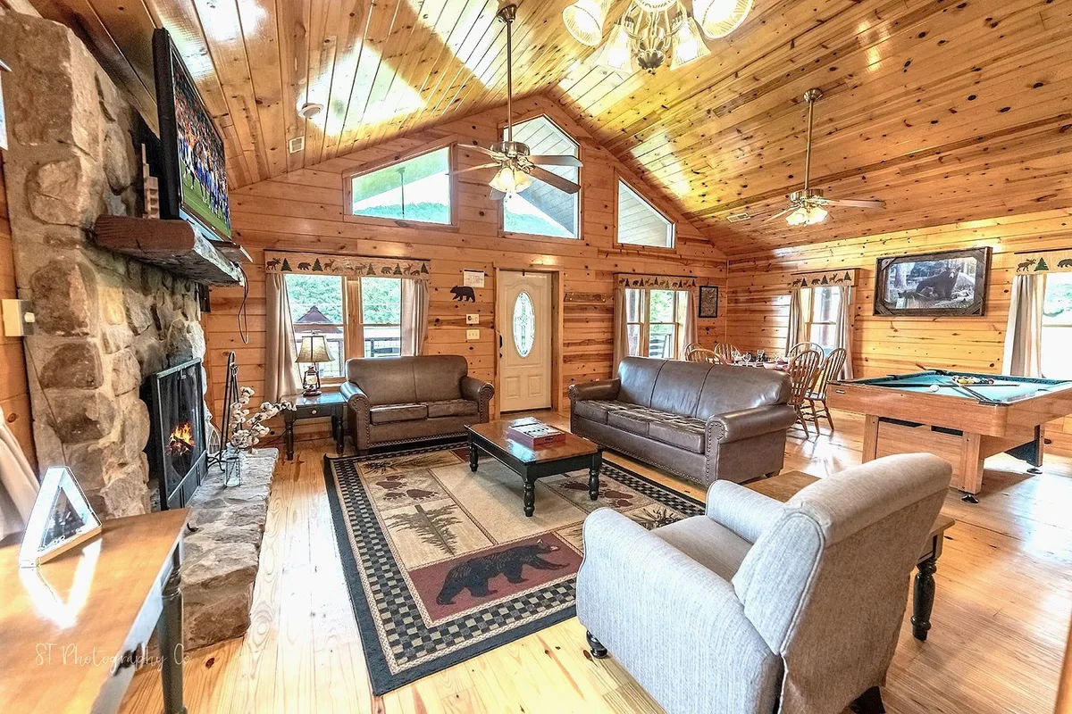 A warm, inviting living room with a stone fireplace, a pool table set for a friendly game, comfortable seating, and a high wooden ceiling. The scene radiates coziness and togetherness, encouraging family bonding and relaxation after a day of adventuring outdoors.